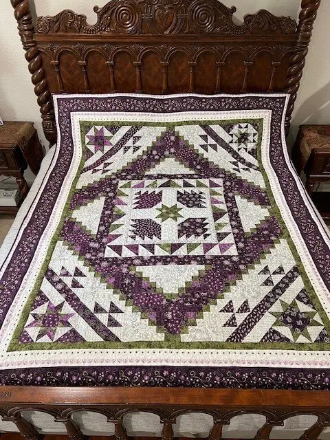 A bed with purple and white quilt on it