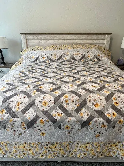 A bed with a quilt on it and two lamps